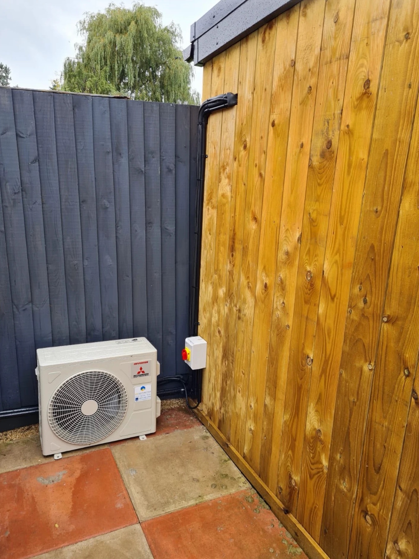 Mitsubishi Electric outdoor unit tucked beside the garden room